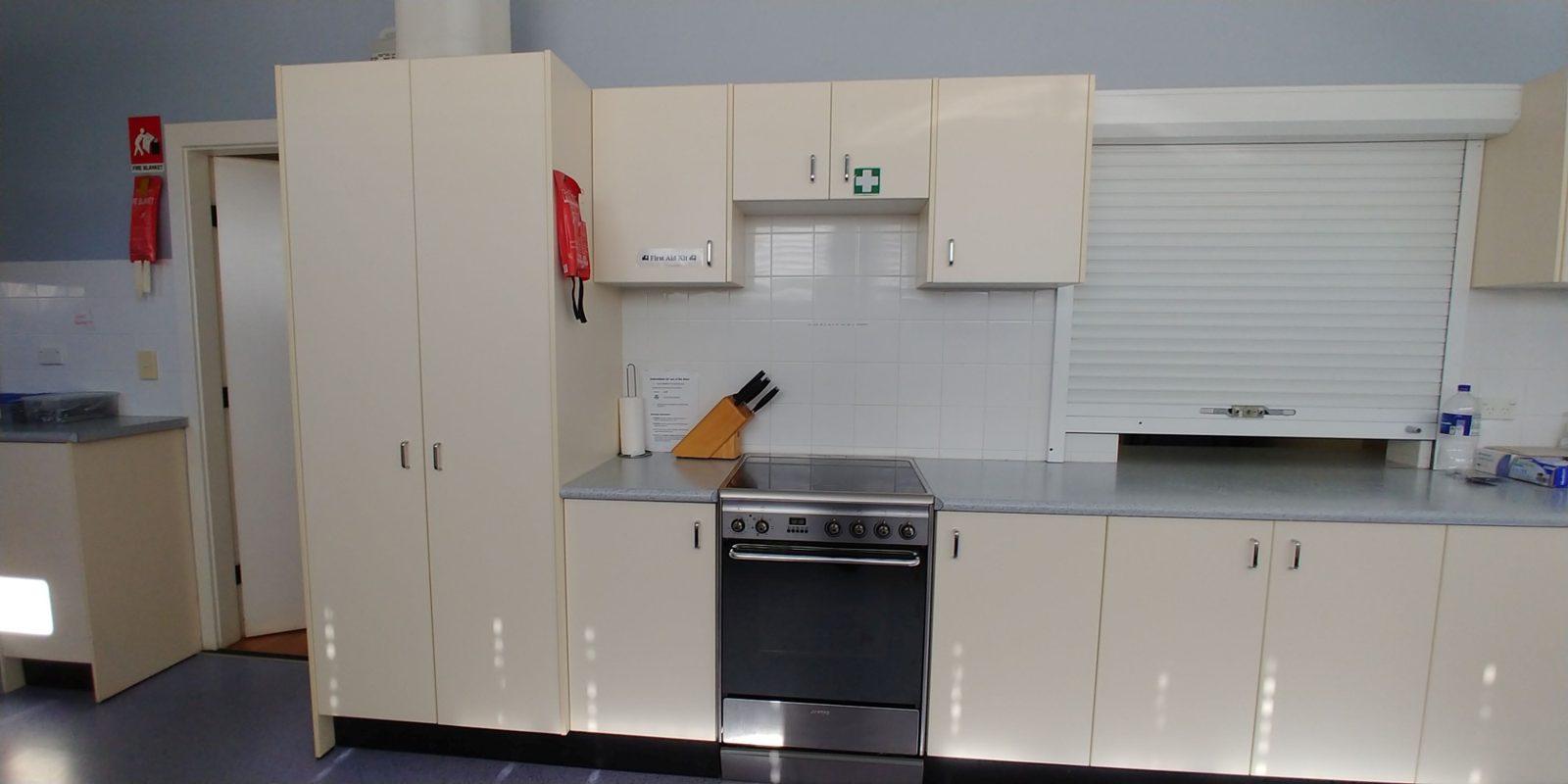 Electric oven and cooktop with a roller-shutter servery above the bench