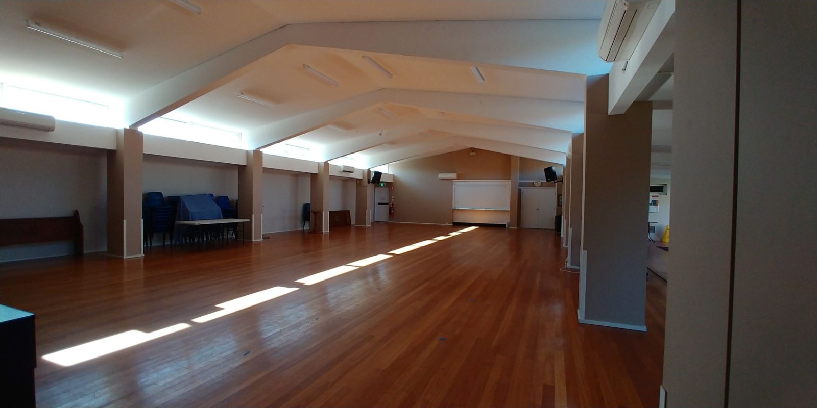The large hall with its raked timber ceiling and polished floor, sunlight across the boards