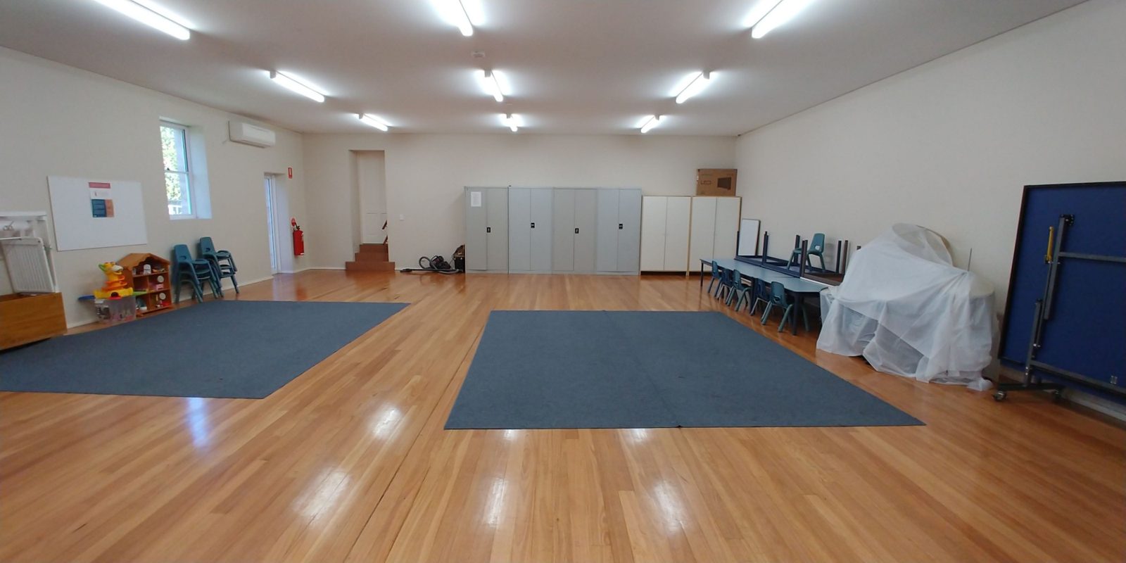 The small hall with carpet squares, storage cupboards and children's chairs