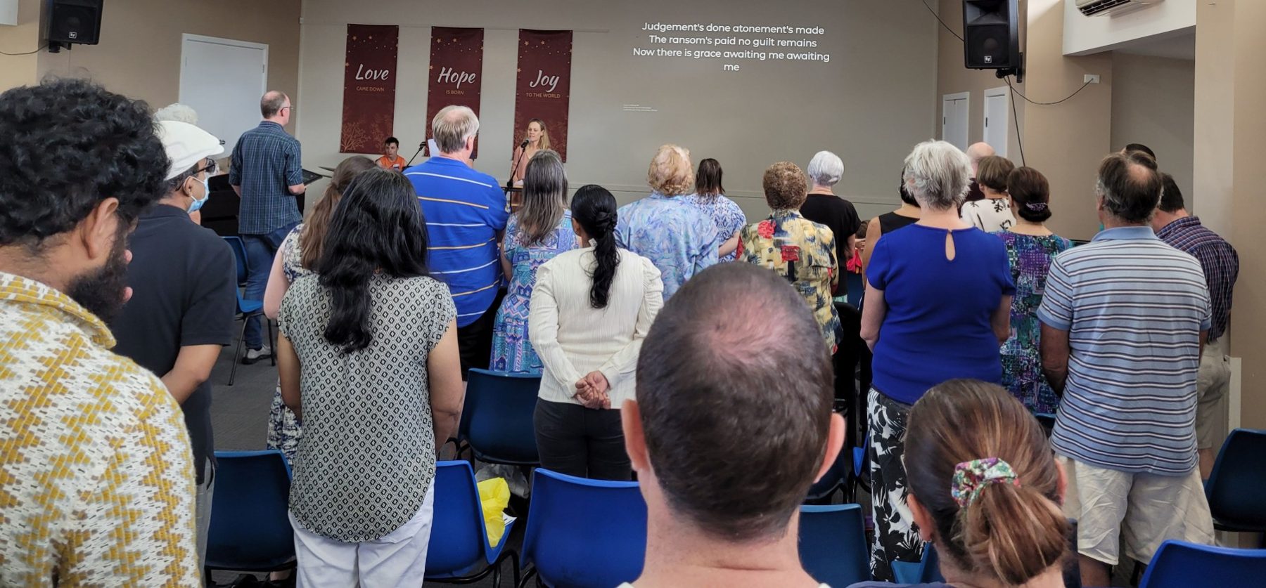 The congregation standing to sing during a Sunday service in the hall
